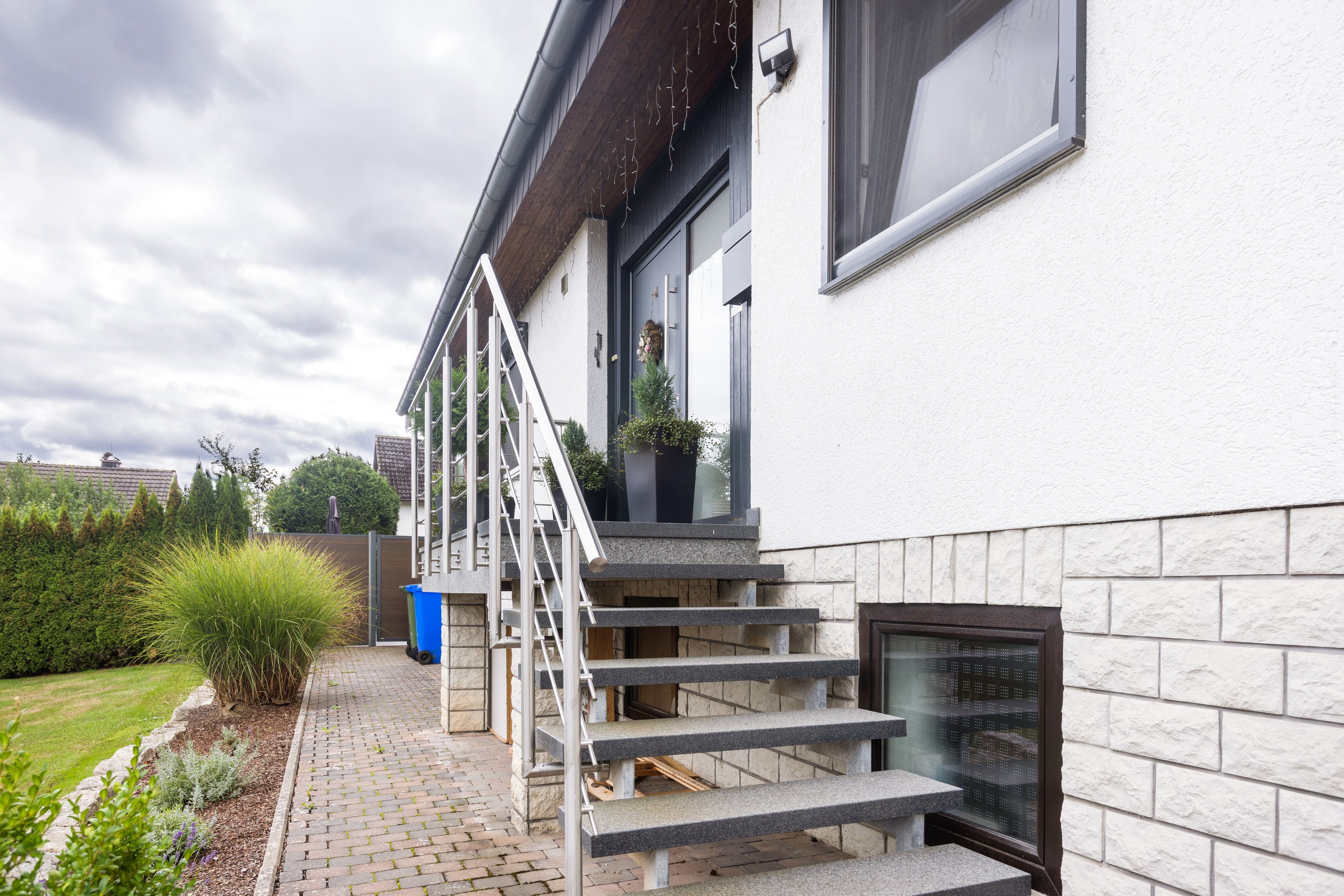 Un immeuble résidentiel doté d’une façade en pierre, d’un escalier extérieur et d’un petit jardin.