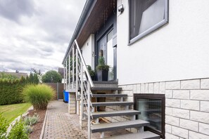 A residential building with a stone facade, a set of outdoor stairs, and a small garden area. - Apartment 'Am Wäldchen' with Shared Terrace, Shared Garden and Wi-Fi (Vöhl)