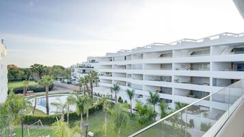A modern hotel with multiple floors, a pool, and lush greenery.
