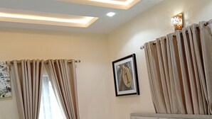 A hotel room with a bed, beige curtains, a framed picture on the wall, and recessed ceiling lighting. - Pinefield Courts Apartmentl  (Akure)