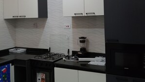 A modern kitchen with white cabinets, a black countertop, a gas stove, a microwave, and a blender. - Pinefield Courts Apartmentl  (Akure)