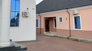 A building with a large window, a door, and an air conditioning unit. - Pinefield Courts Apartmentl  (Akure)