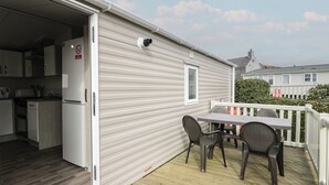Une maison mobile comprenant un coin cuisine, une table à manger avec des chaises et une terrasse.