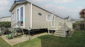 Une maison mobile de plain-pied dotée d’une terrasse à l’avant et d’un petit espace patio.