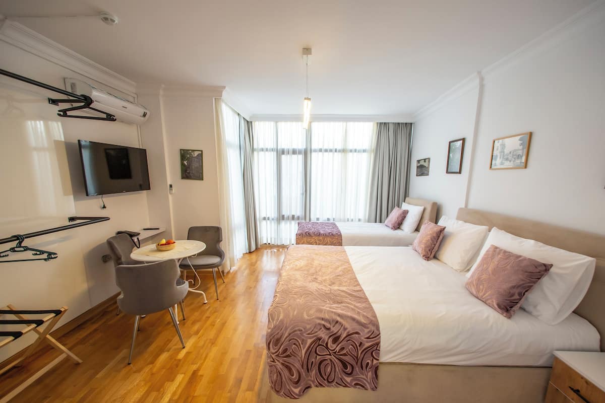 A hotel room with a bed, a desk, a chair, a TV, and a window with curtains.