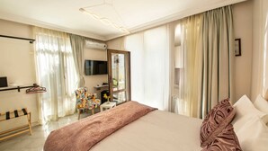 A hotel room with a large bed, a TV, a desk, and a chair. - Poseidon Kinaliada Pansiyon (Adalar)