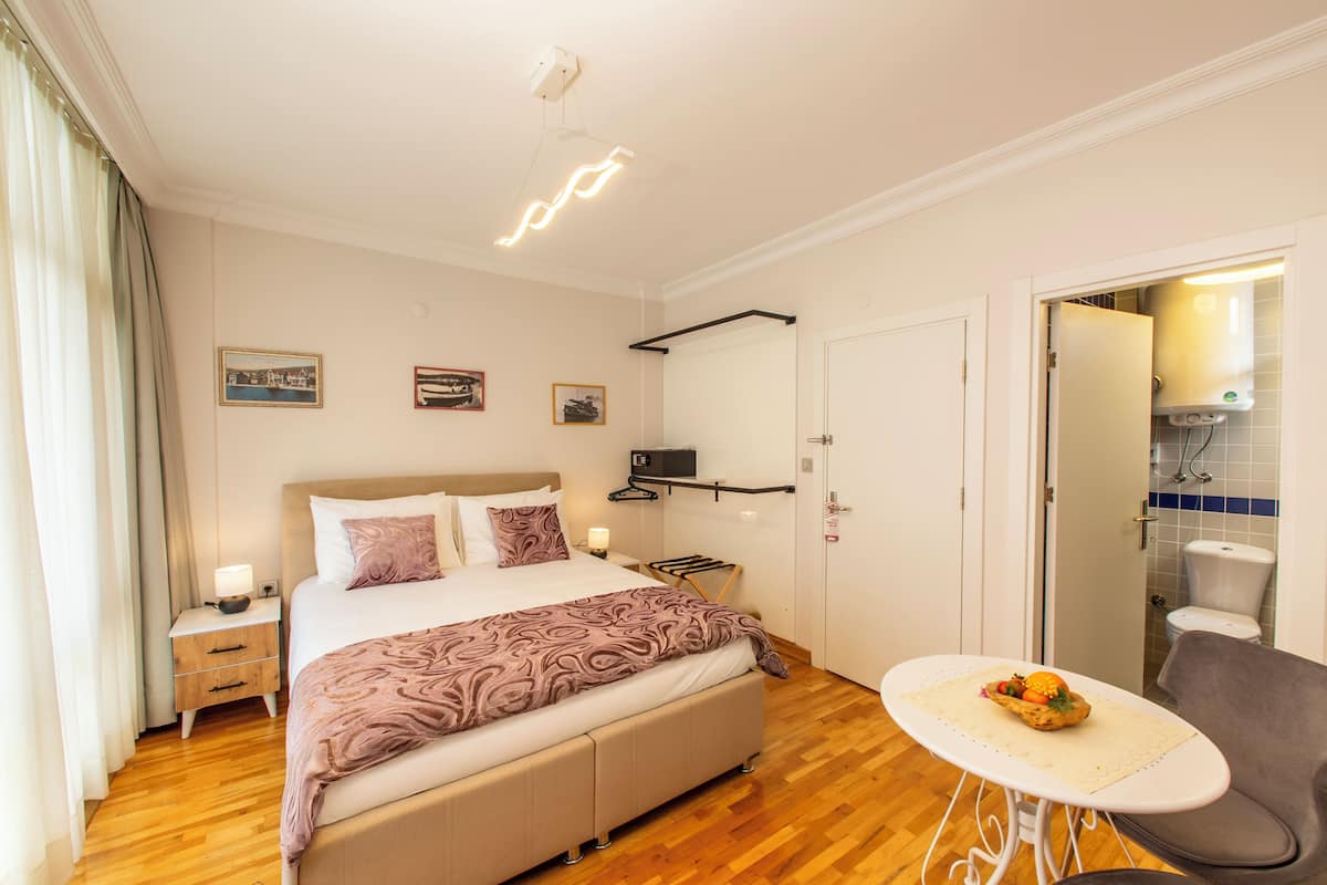 A neatly arranged bedroom with a bed, bedside tables, a small table with fruit, and a chair.