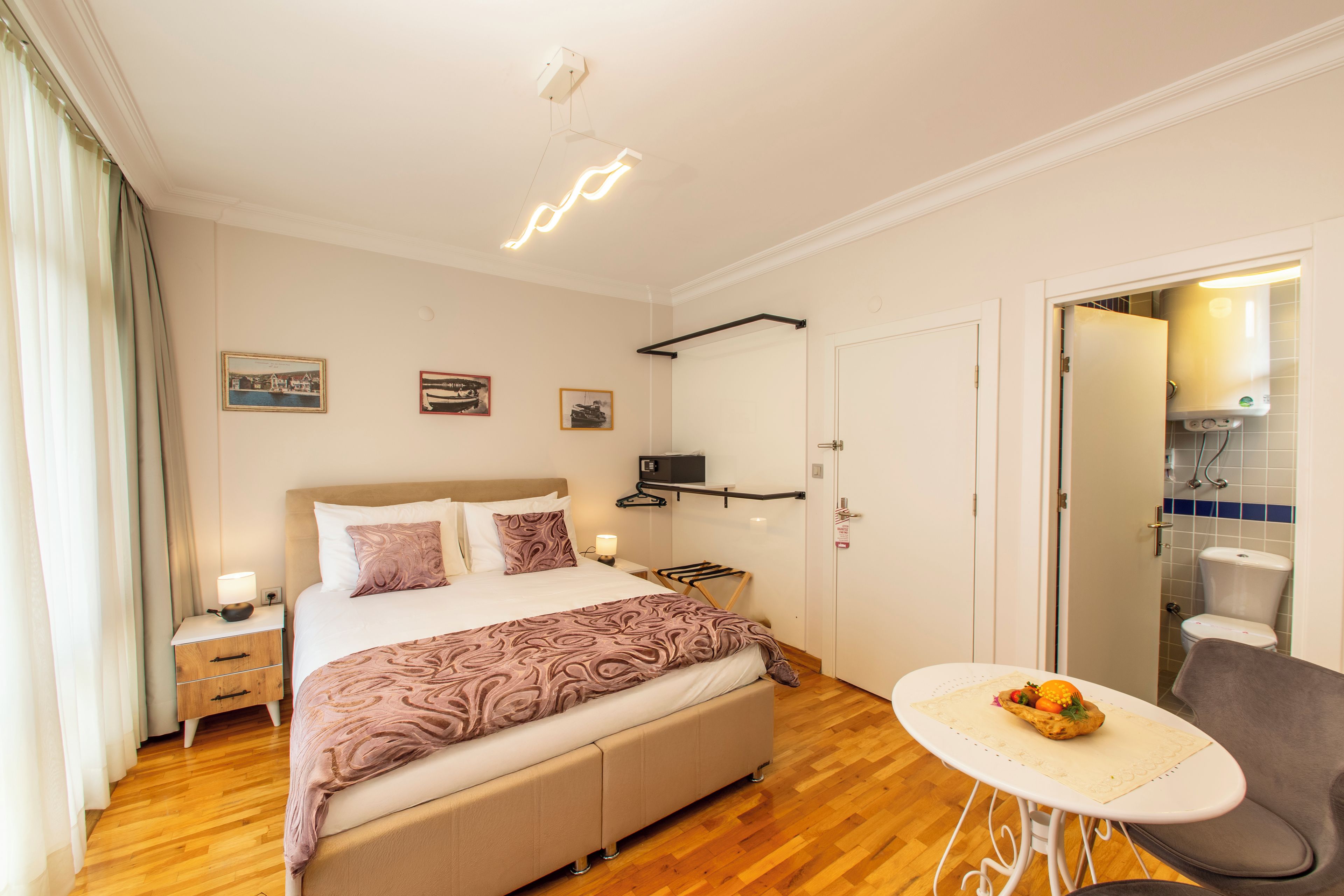 A neatly arranged bedroom with a bed, bedside tables, a small table with fruit, and a chair.