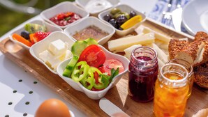 A wooden board with various food items including cheese, bread, and vegetables. - Poseidon Kinaliada Pansiyon (Adalar)