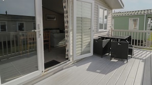 Una habitación con una cama, una silla y una mesa en una terraza de madera.