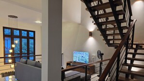 Un salon moderne avec une grande fenêtre, un canapé, un téléviseur et un escalier en bois.