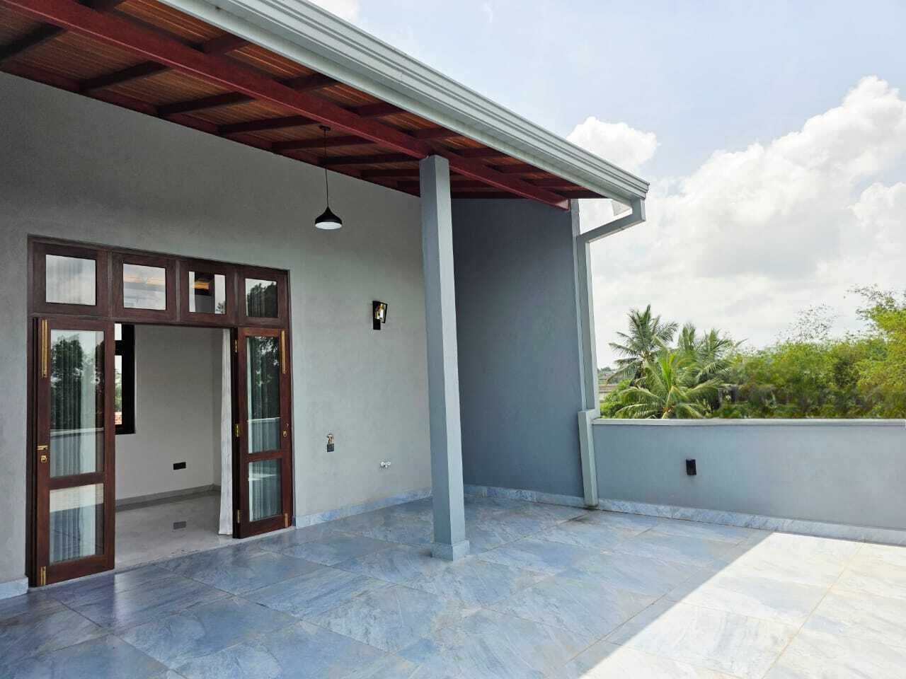 A spacious outdoor area with a covered patio, a large open door, and a view of greenery in the background.