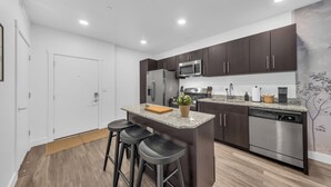 A modern kitchen with dark cabinets, stainless steel appliances, and a central island with bar stools.