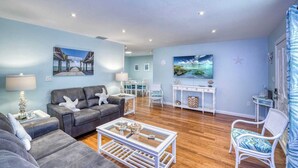 A living room with a grey sofa, a white coffee table, and a dining area with a white table and chairs. - 3 miles to AMI beach, 3 bed 2 bath, 4 miles to IMG (Bradenton)