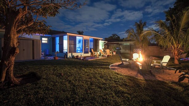 A modern house with large windows, a patio area with outdoor furniture, and a well-maintained lawn. - 3 miles to AMI beach, 3 bed 2 bath, 4 miles to IMG (Bradenton)