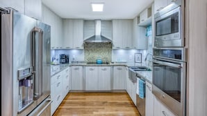 A modern kitchen with stainless steel appliances, white cabinetry, and a granite countertop. - 3 miles to AMI beach, 3 bed 2 bath, 4 miles to IMG (Bradenton)