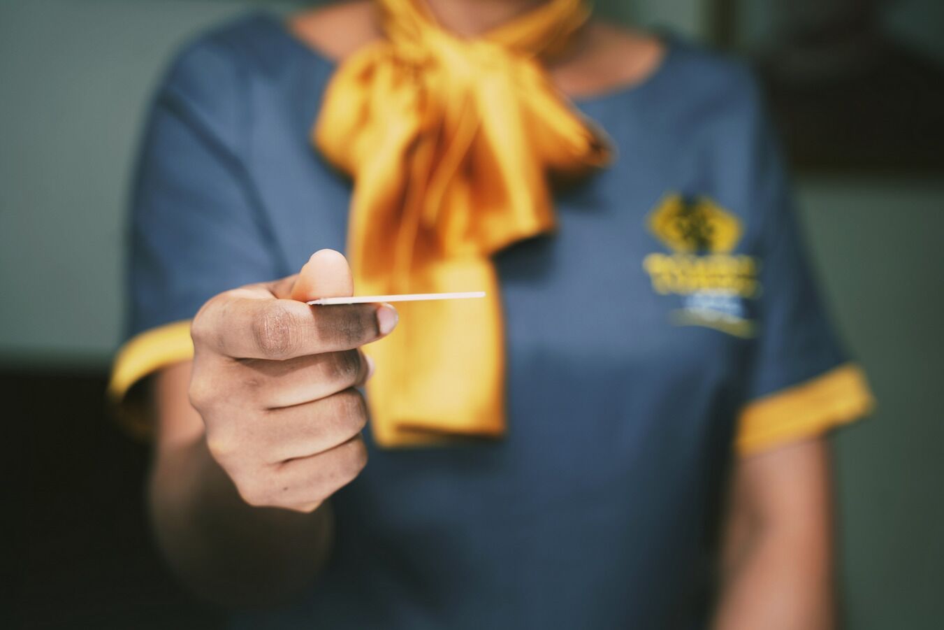 A person wearing a blue shirt with a yellow bow tie and a logo on the chest.