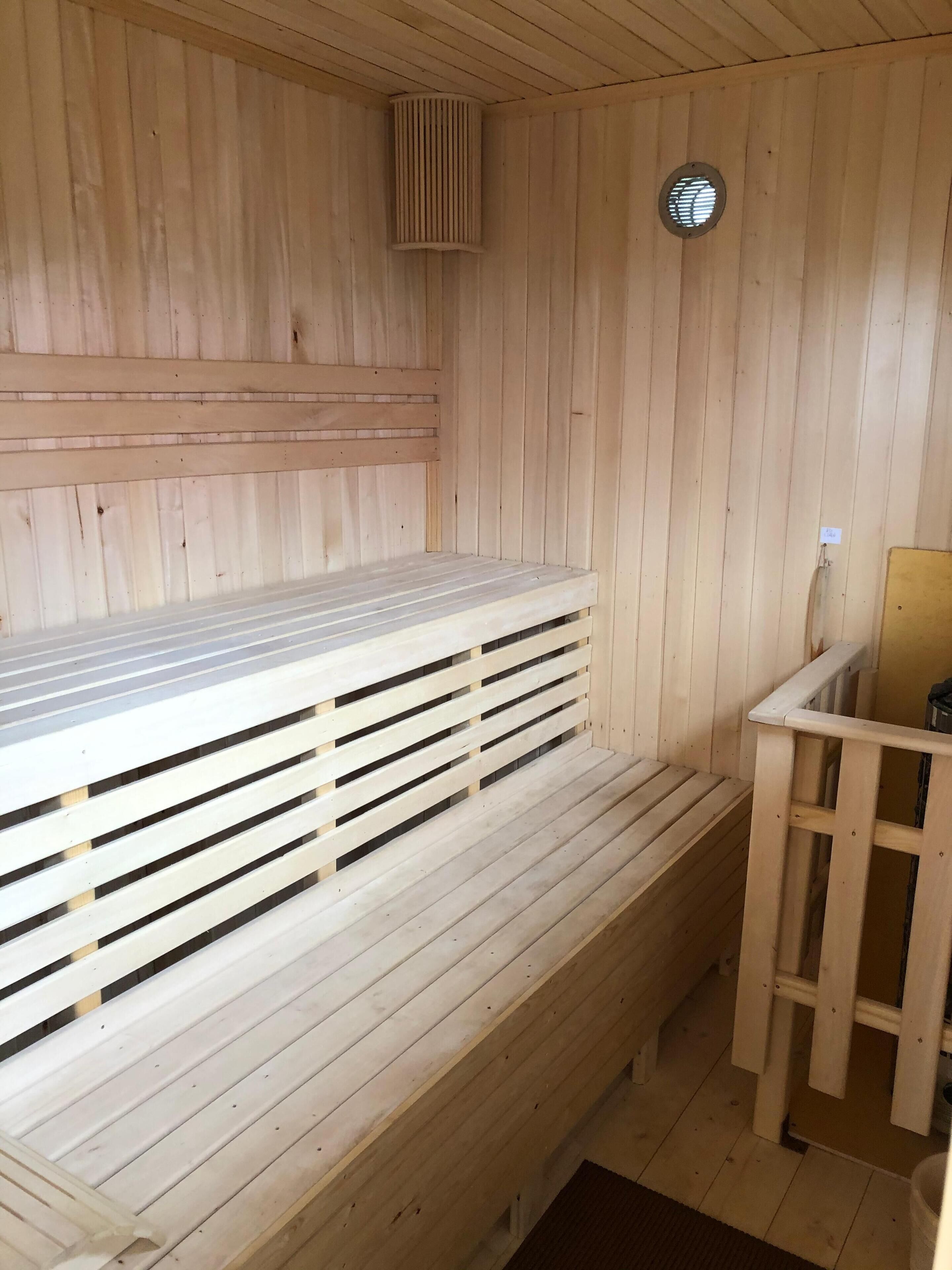 En träbeklädd bastu med bänkar och en liten sittplats.