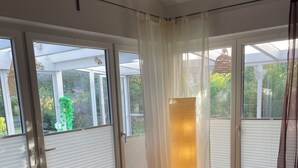 Una habitación con grandes puertas correderas de vidrio, una lámpara de pie y una silla de madera.