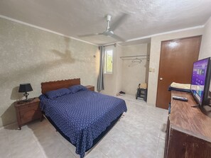 A bedroom with a bed, a desk, a chair, a TV, and a ceiling fan. - Apartment next to the estuary of Progreso! Near the ecopark El Corchito (Progreso)