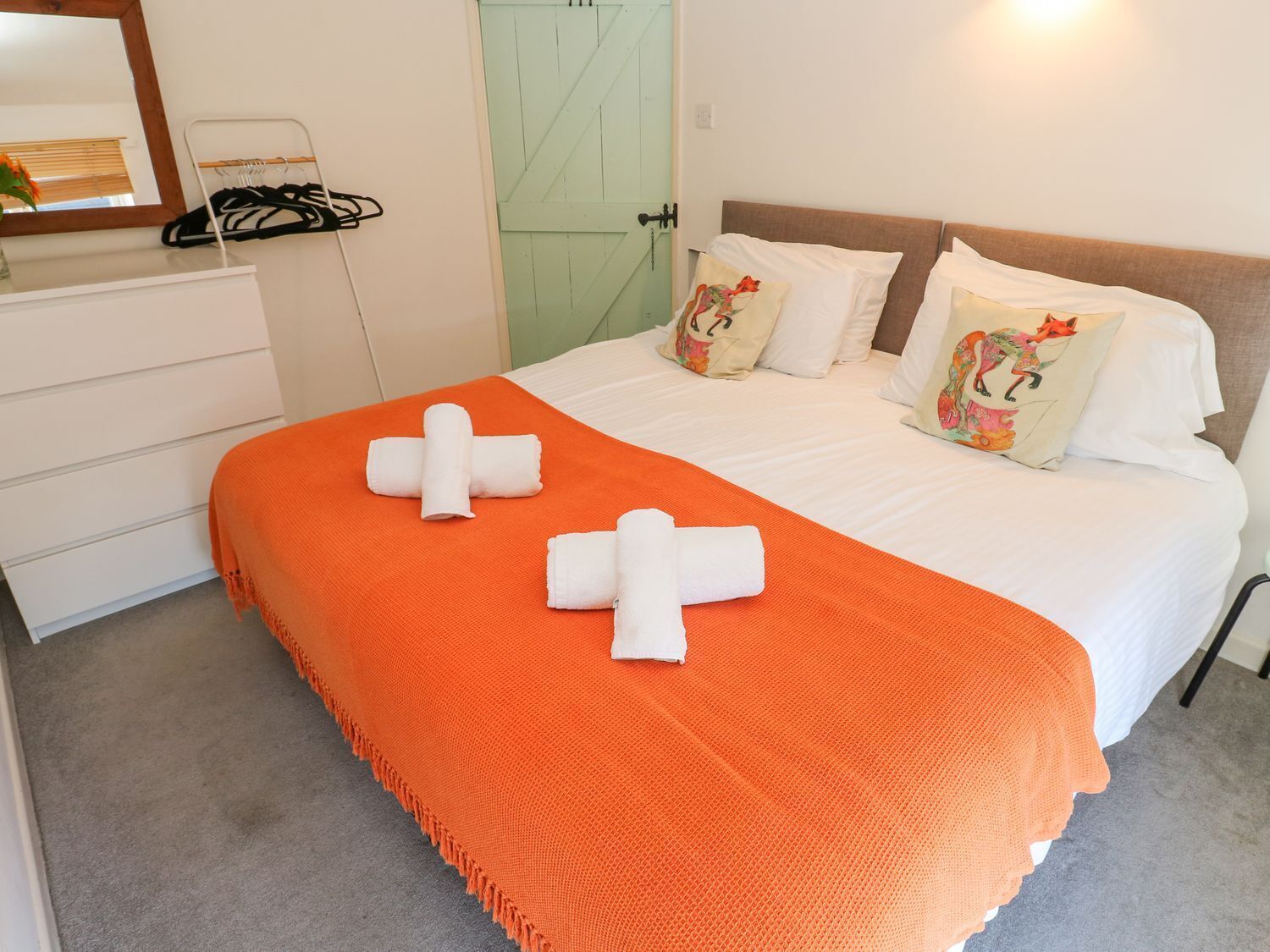 A hotel room with a bed, two pillows, a nightstand, and a mirror.