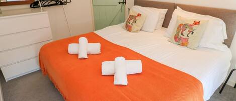 A hotel room with a bed, two pillows, a nightstand, and a mirror.