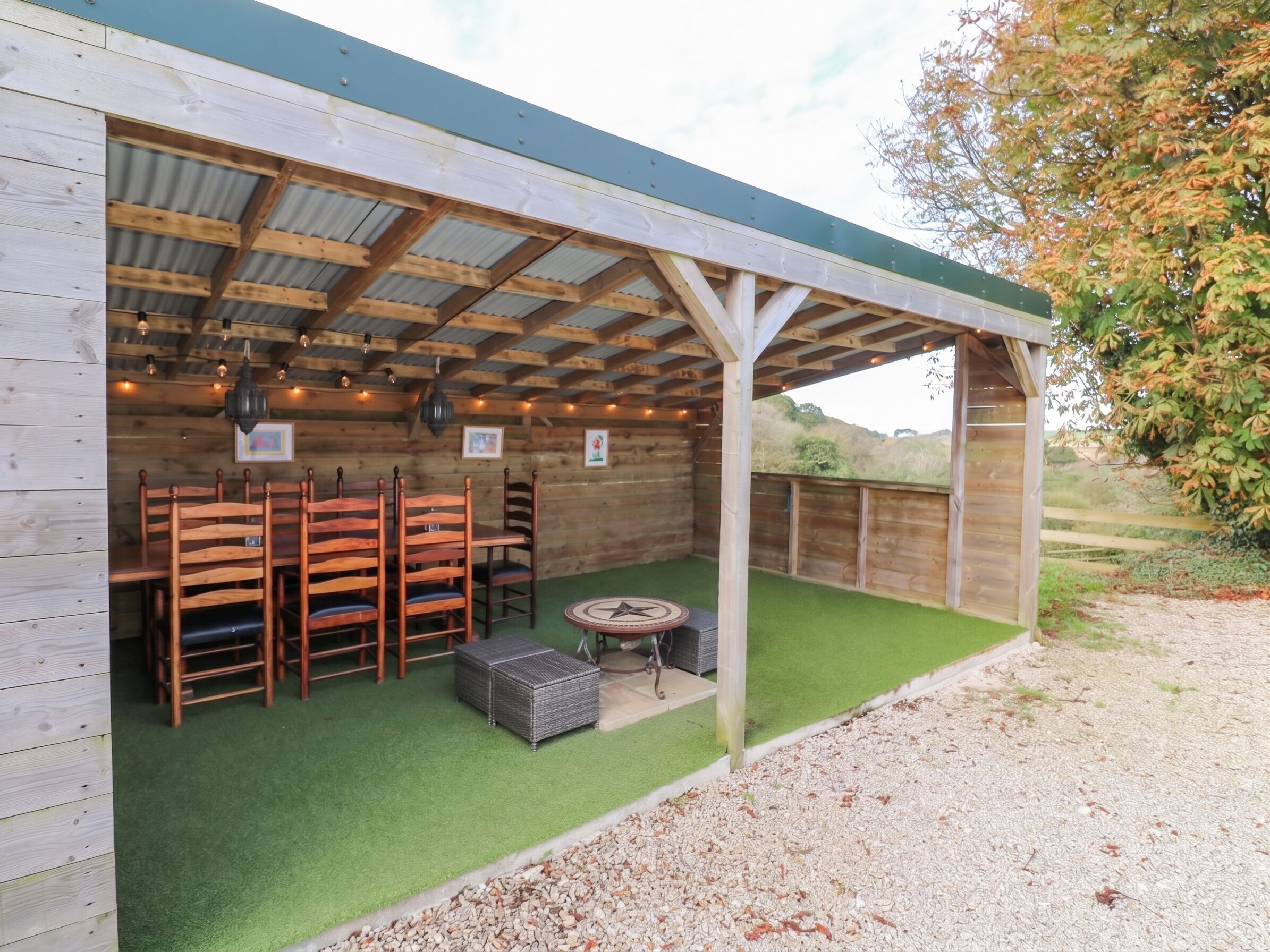 Un espacio de estar techado al aire libre con sillas de madera y una mesa redonda.