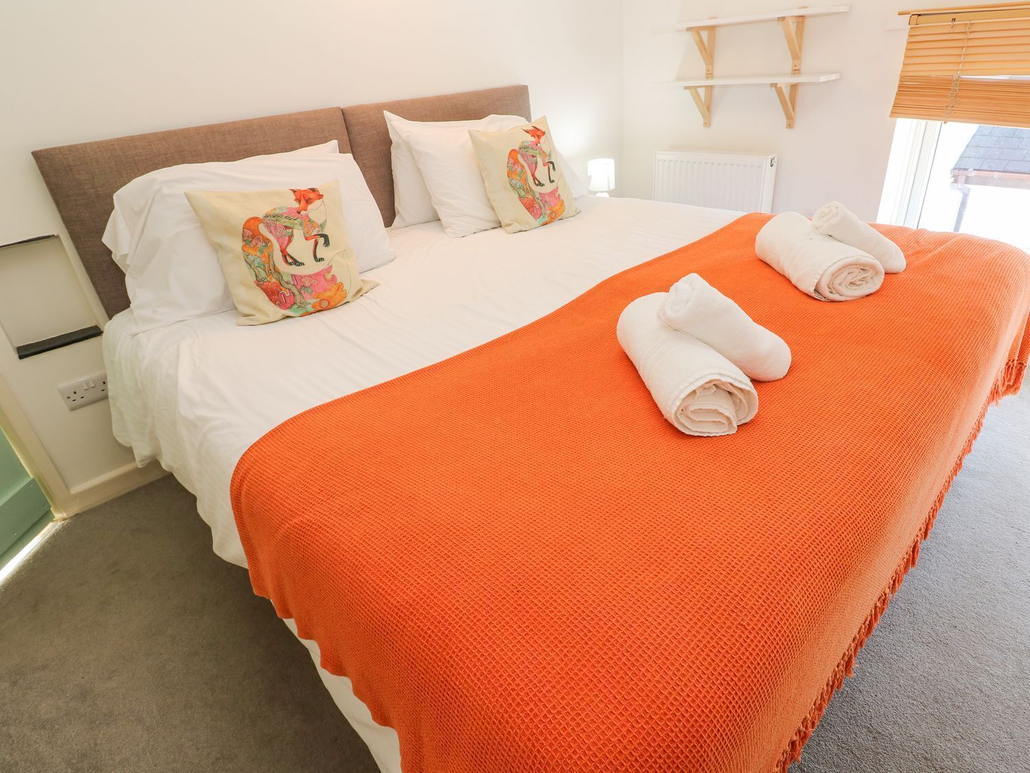 A hotel room with a bed, pillows, and a blanket.
