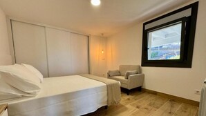 A bedroom with a bed, a chair, a window, and a radiator. - Cíes Suitel Prado (Nigrán)