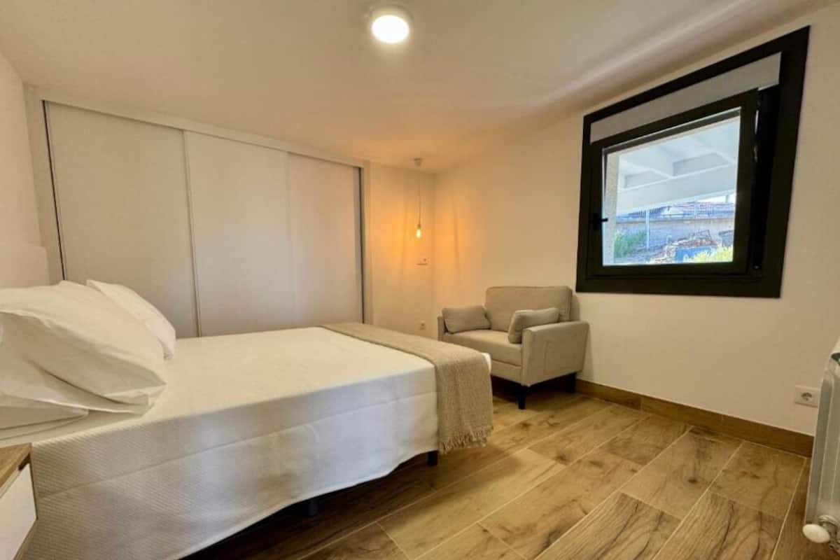 Une chambre à coucher avec un lit, une chaise, une fenêtre et un radiateur.