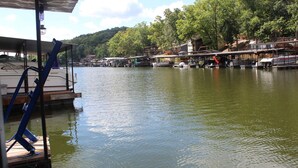 A docked boat with a covered area and a wooden deck. - Cozy Lake House with a Private dock and beautiful outdoor space. (Rocky Mount)