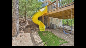 A yellow slide extending from a wooden deck into a stone building. - Cozy Lake House with a Private dock and beautiful outdoor space. (Rocky Mount)
