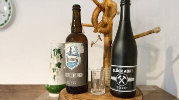 Twee flessen bier, een glas en een bretzel op een houten ondergrond.