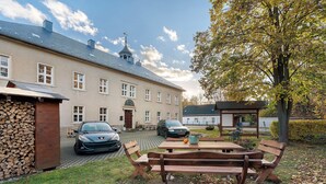 Rakennus, jonka edessä on asfaltoitu ajotie, piknikpöytä ja pysäköity auto.