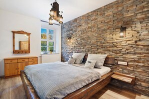 Une chambre avec un mur en pierre, un lit en bois et une fenêtre donnant sur un beau paysage.