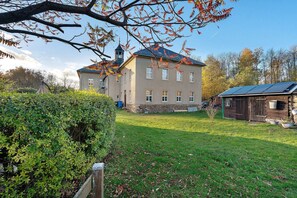 Un grand bâtiment doté d’une tour, entouré d’une pelouse bien entretenue et d’un petit abri de jardin.