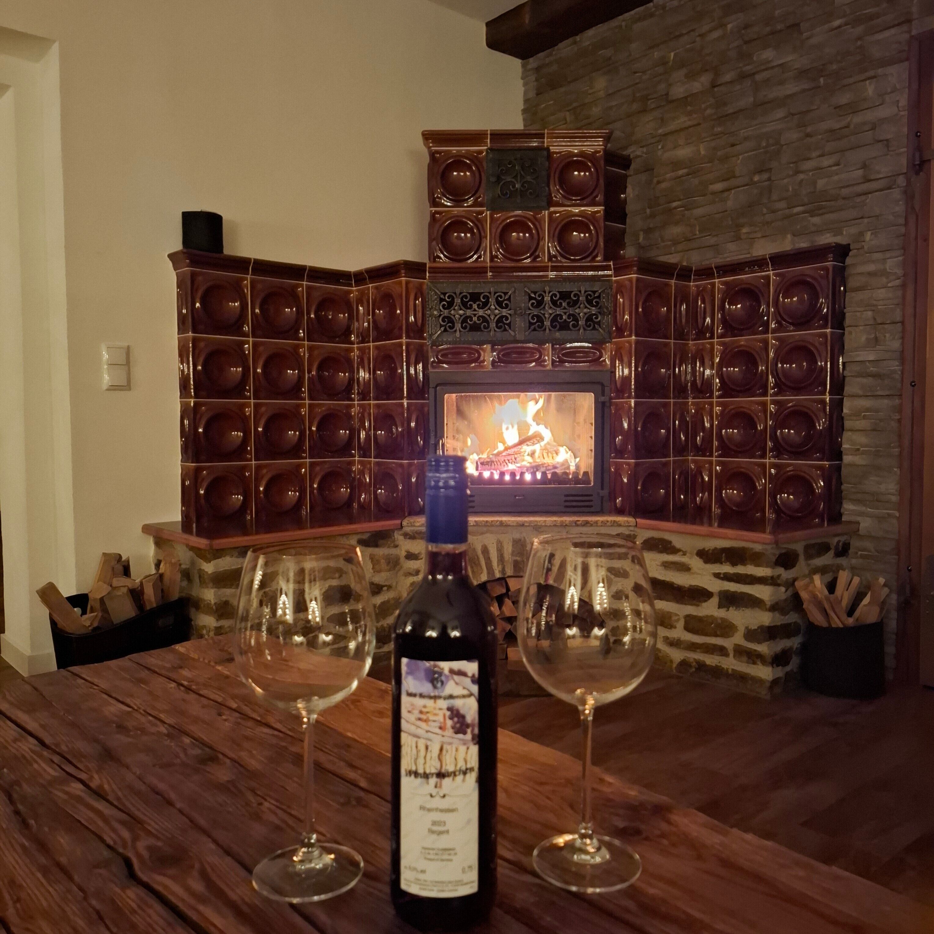 Una chimenea con revestimiento de piedra, una botella de vino y dos copas de vino sobre una mesa de madera.