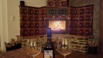 Una chimenea con revestimiento de piedra, una botella de vino y dos copas de vino sobre una mesa de madera.