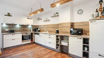 A modern kitchen with white cabinets, wooden flooring, and a built-in oven.