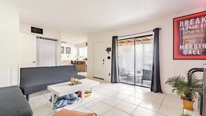 A modern living room with a sofa, a coffee table, and a sliding glass door leading to a balcony. - Wall Street Retreat - Modern , Luxury, Near Beach! (Port Orange)