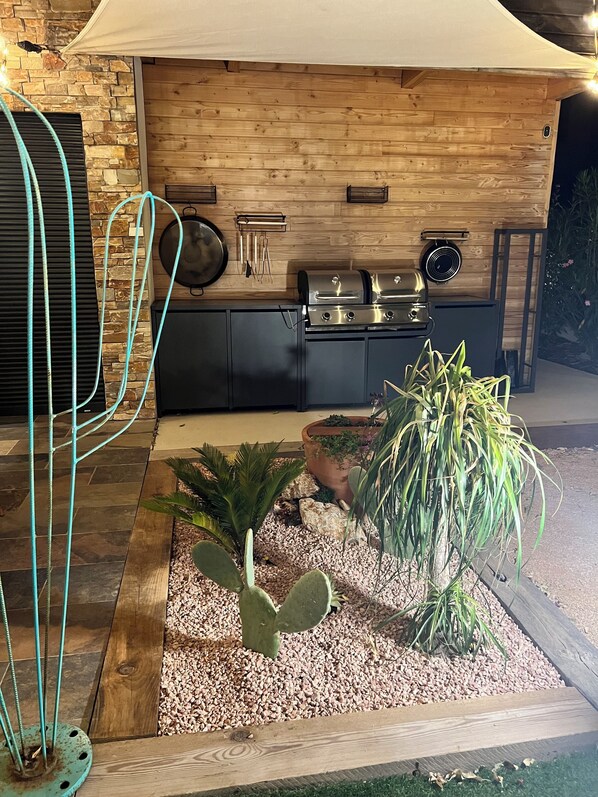 A modern kitchen with a stone wall, wooden cabinets, and a built-in grill. - Contemporary house with heated pool, close to beaches and calanques (Gémenos)