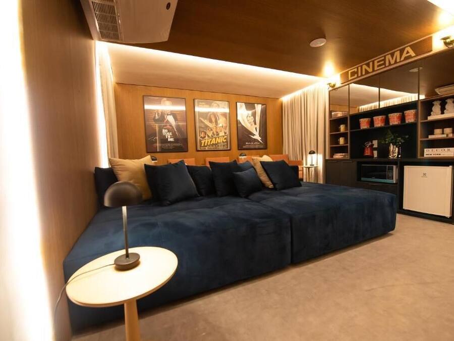 A cozy room with a dark blue sofa, a small round table, and a bookshelf labeled "CINEMA" with movie posters.