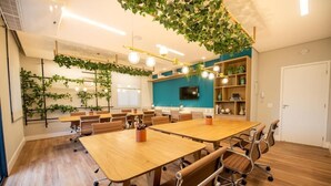 A modern conference room with wooden tables, chairs, and a ceiling garden. - Studio completo Vl Olimpia Be my Guest (São Paulo)