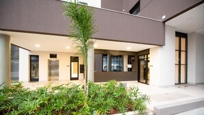A modern building with a covered outdoor area featuring a small garden with various plants and a central tree. - Studio completo Vl Olimpia Be my Guest (São Paulo)