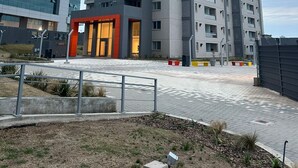 Un immeuble résidentiel de grande hauteur, doté de nombreux balcons et d’une entrée moderne.
