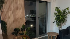 Un salon moderne avec une table en bois, deux chaises, un canapé foncé et une plante en pot.