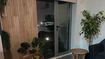 Una sala de estar moderna con una mesa de madera, dos sillas, un sofá oscuro y una planta en maceta.