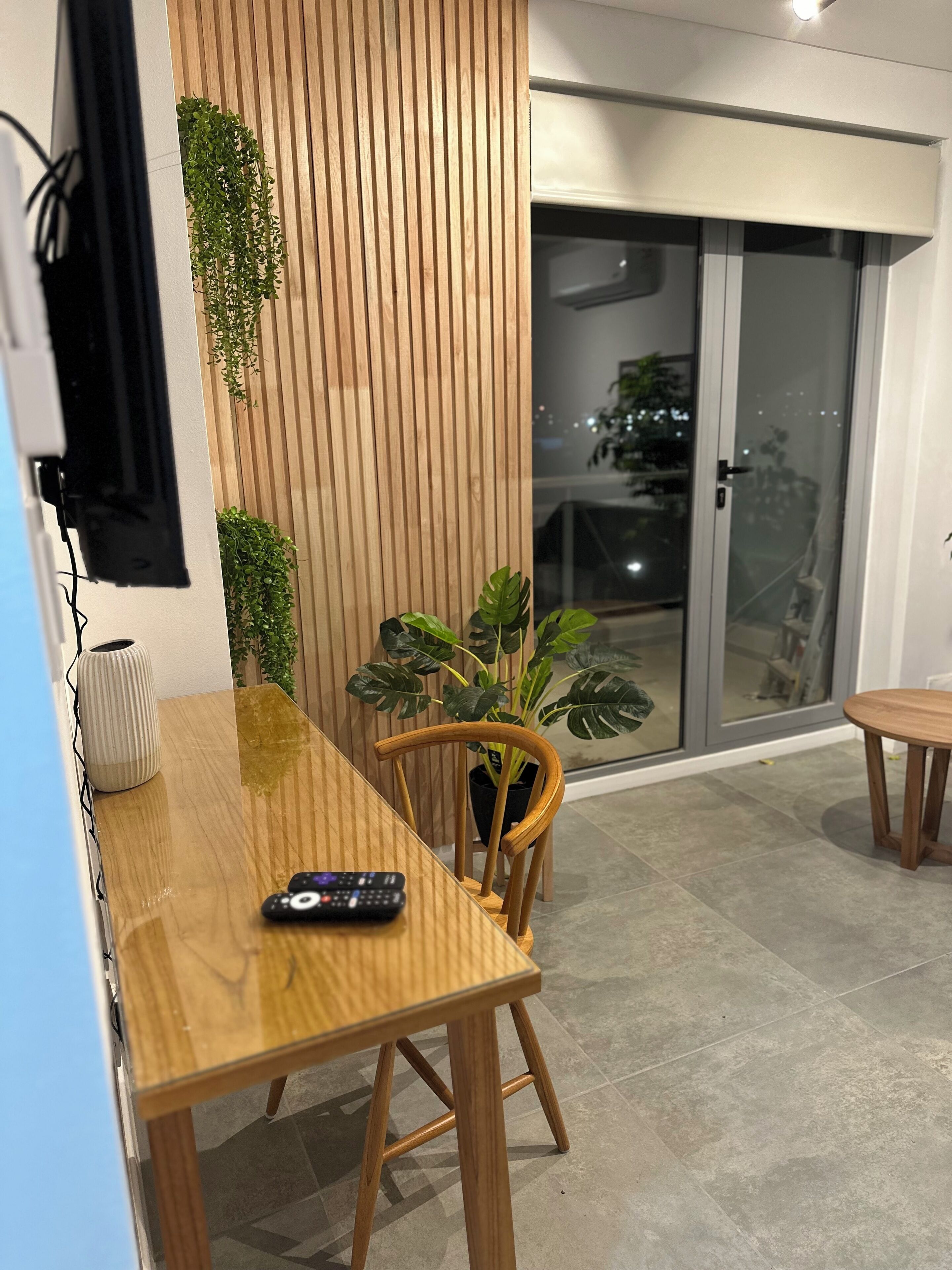 Un comedor moderno con una mesa de madera, sillas y un control remoto sobre la mesa.