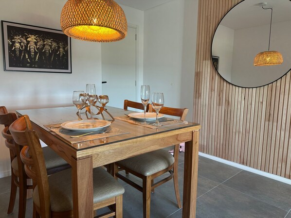 Un comedor con una mesa de madera dispuesta para cuatro personas, rodeada de sillas.