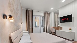 Een moderne slaapkamer met een groot bed, een aan de muur bevestigde televisie en een bureau met stoel.